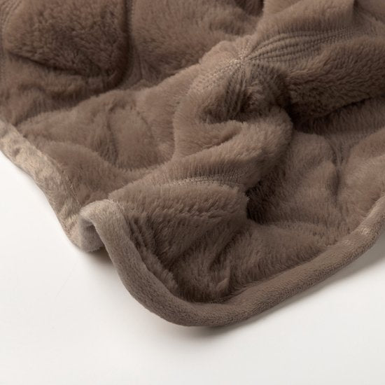 Detail van het gewatteerde bloemmotief op de taupe bedsprei