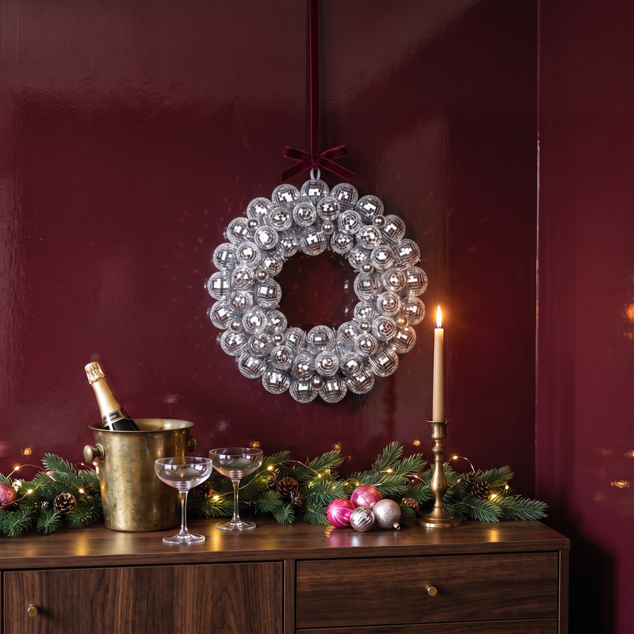 Kerstkrans discoballen zilver 40 cm aan een bordeaux muur met champagne en kerstgroen