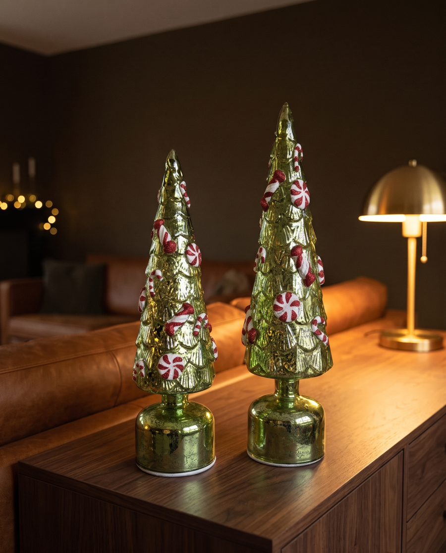 Groene glazen LED kerstbomen met zuurstokken op dressoir in warme woonkamer
