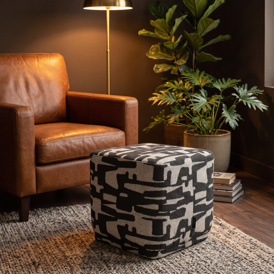 Vierkante poef grafische print zwart als voetenbank bij cognac fauteuil