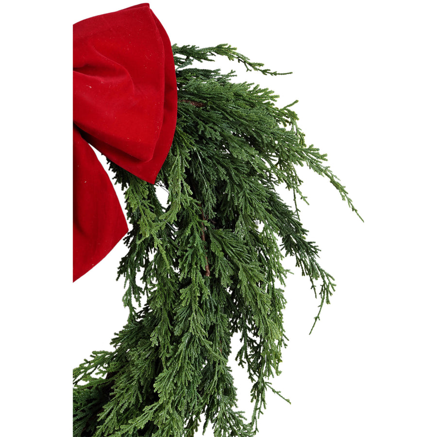 Detail van de cipressentakken en de rode fluwelen strik van de kerstkrans