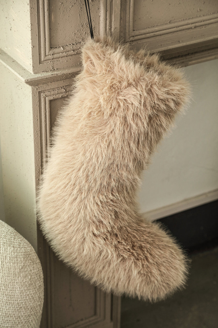 Beige kerstsok van imitatiebont aan de schouw, sfeerfoto