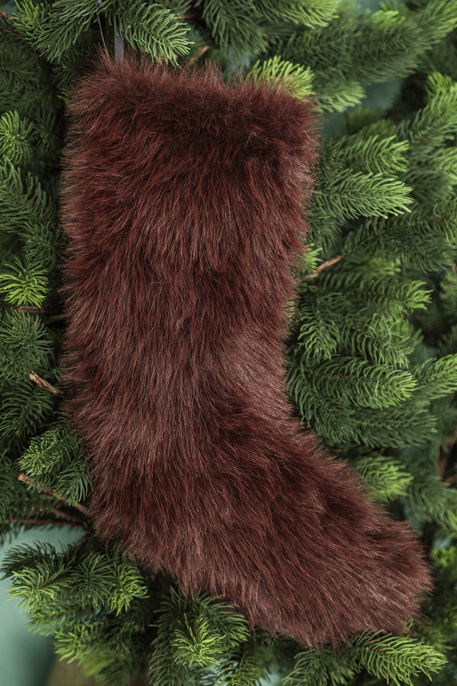 Donkerbruine kerstsok van imitatiebont in de kerstboom, sfeerfoto